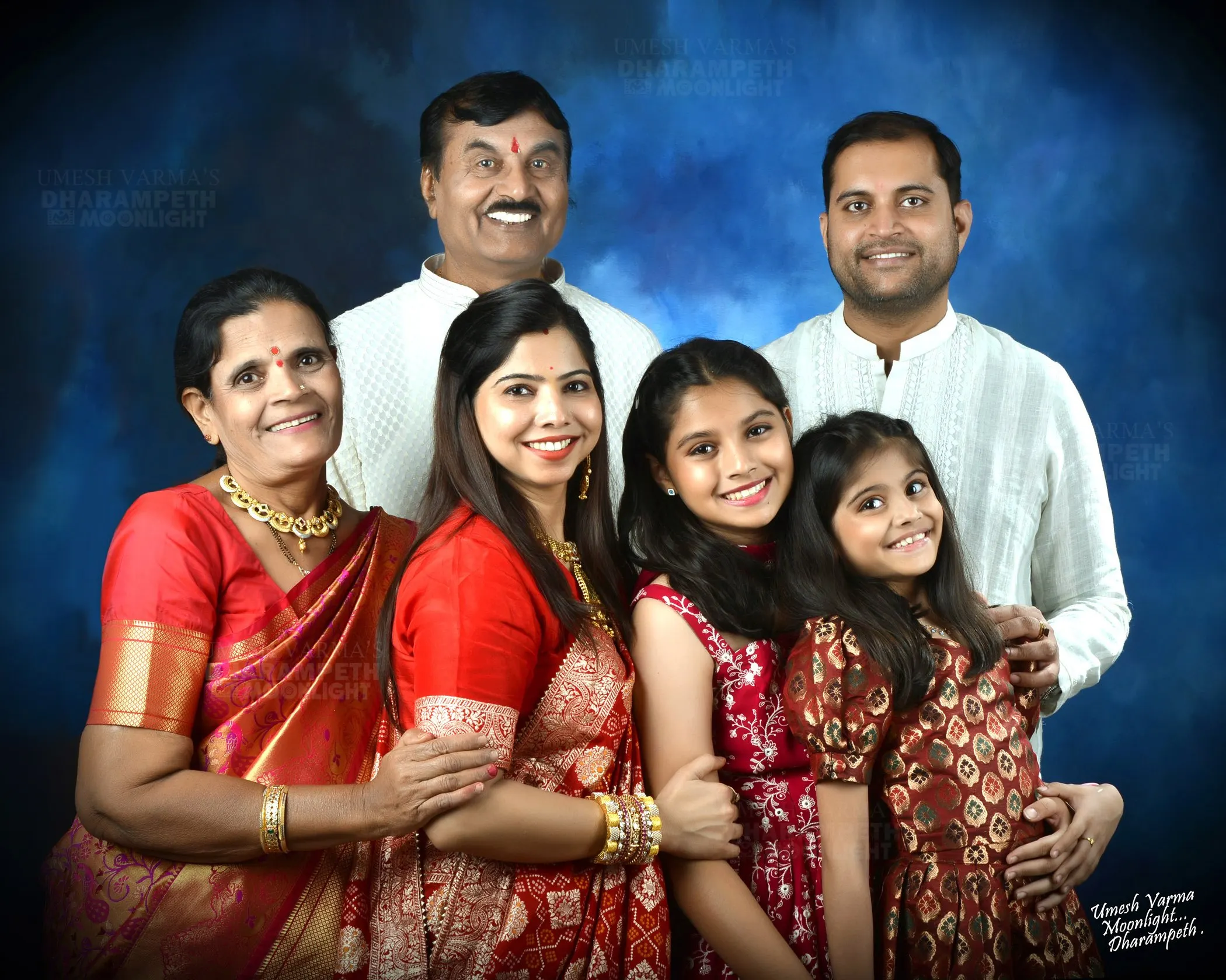 Joint family of seven against a blue painted backdrop