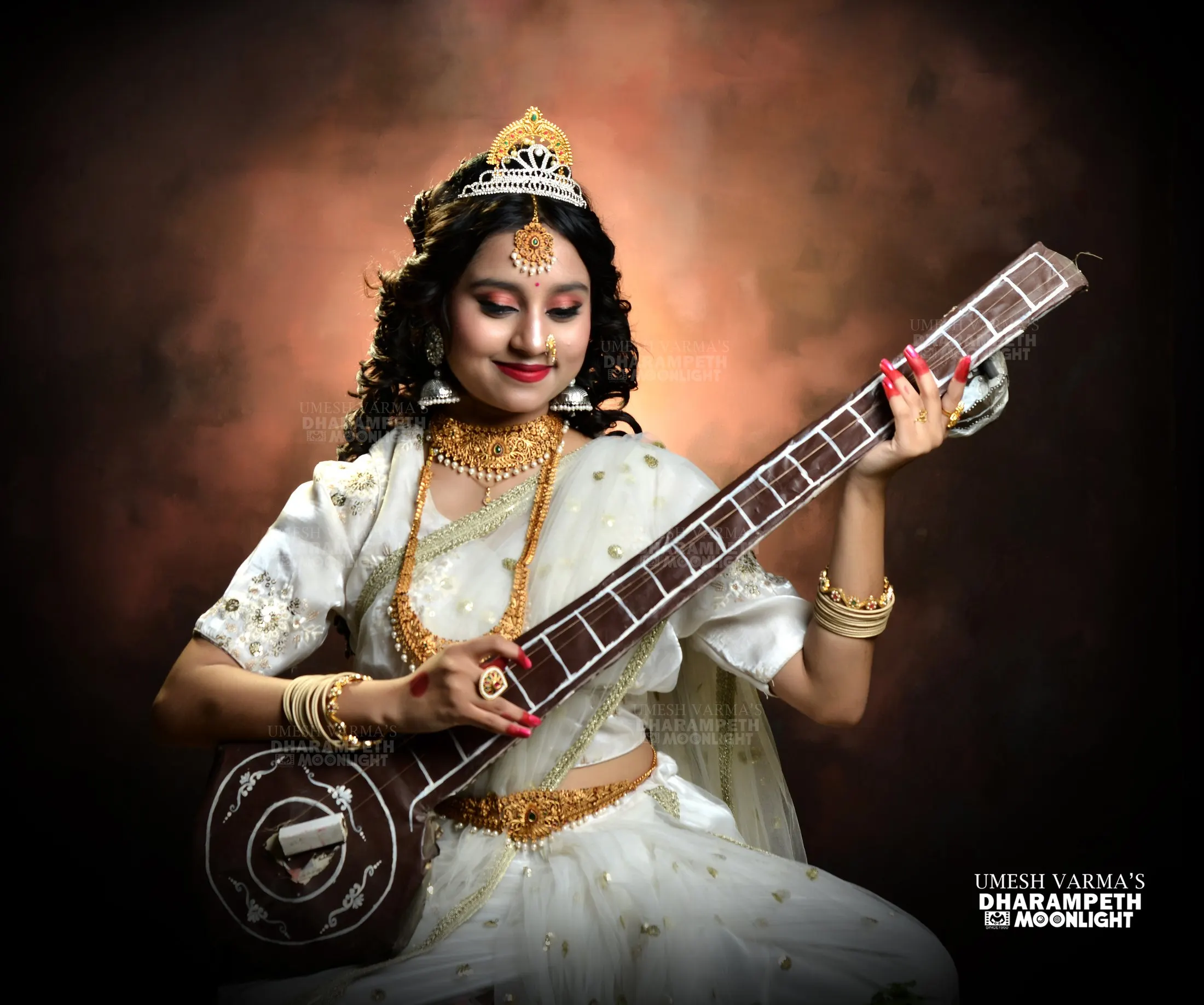 Themed portrait of a girl dressed as Goddess Saraswati playing the veena
