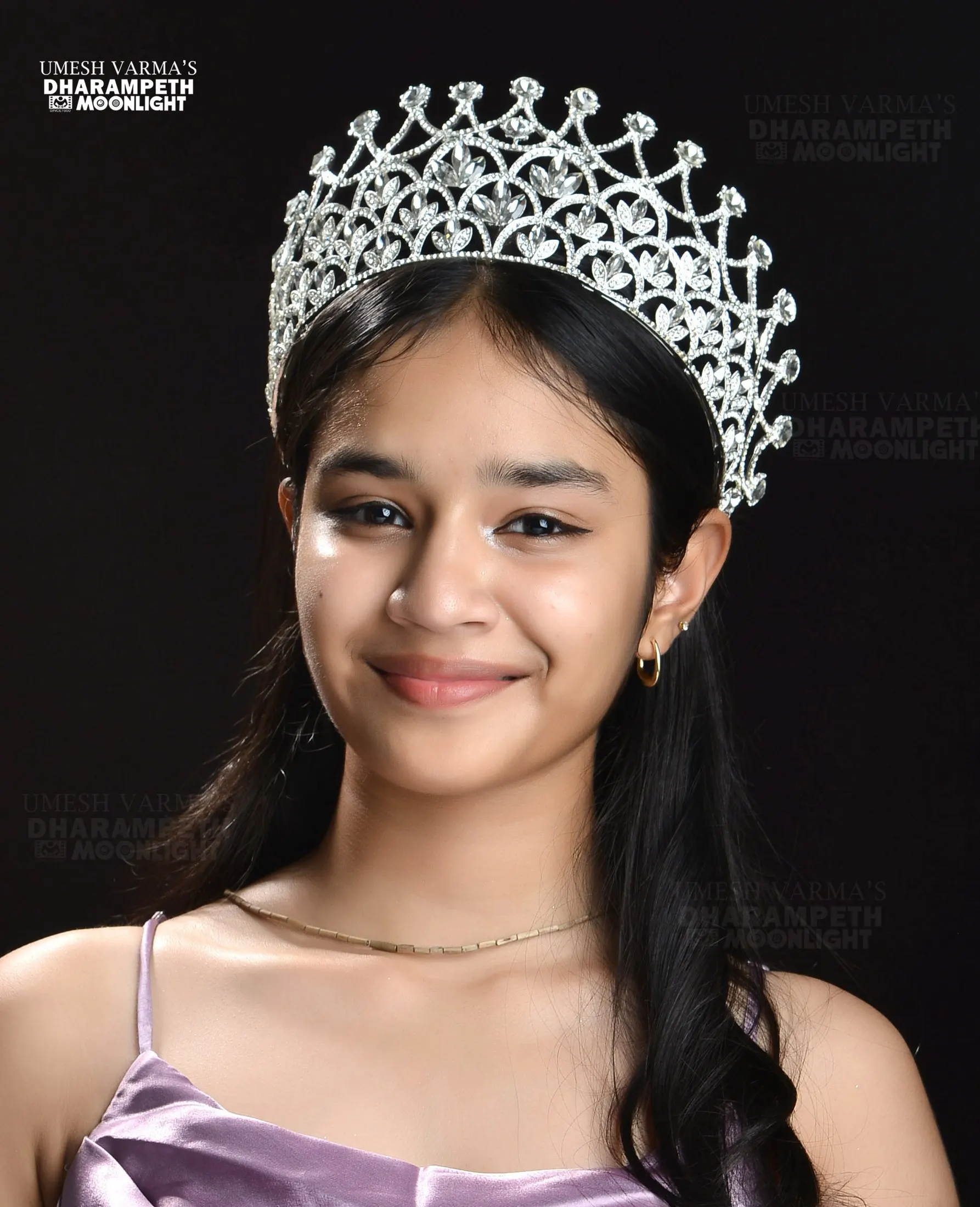 Teenage girl wearing a crystal tiara against a dark backdrop