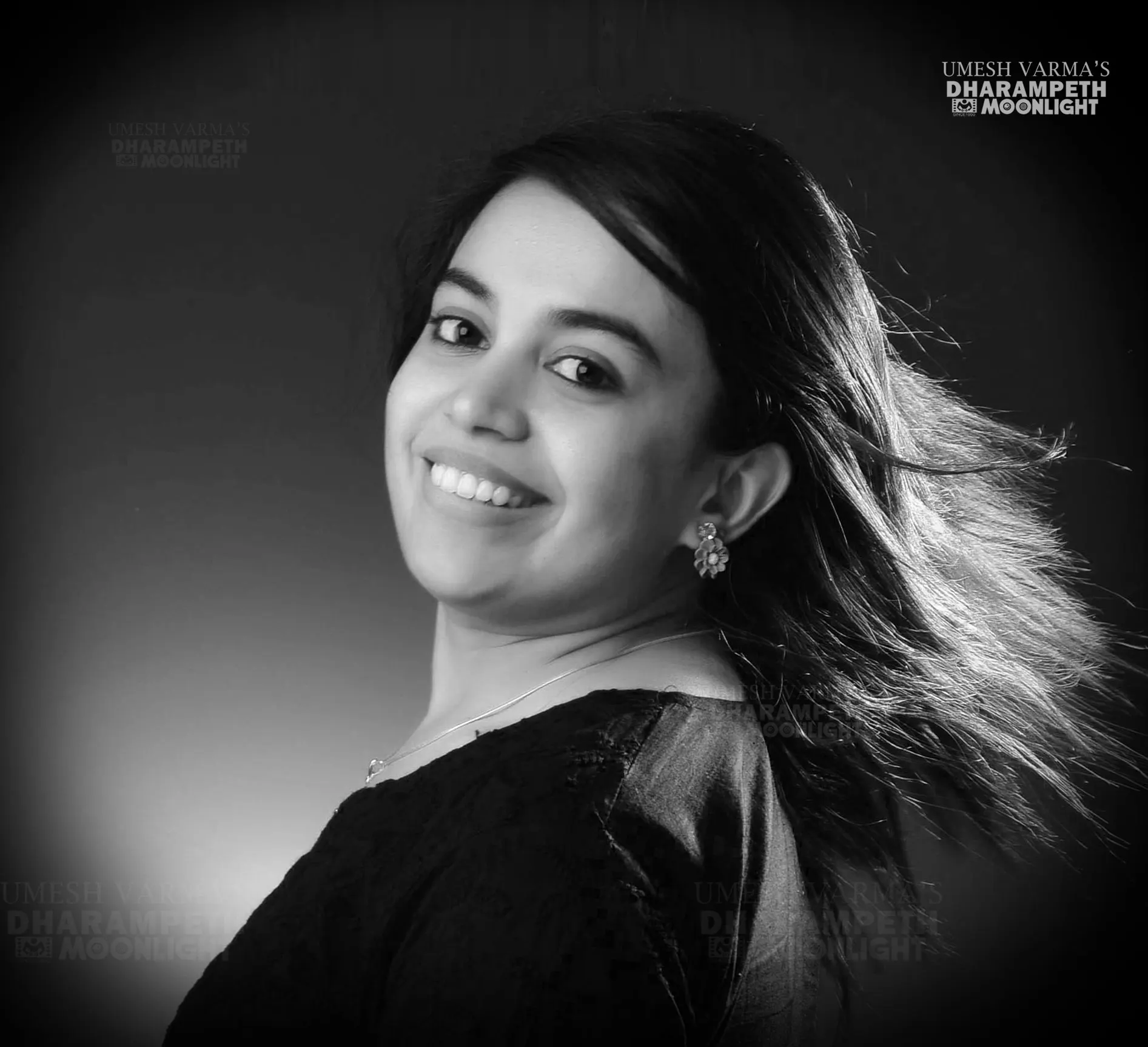 Black and white portrait of a smiling woman with her hair swept back